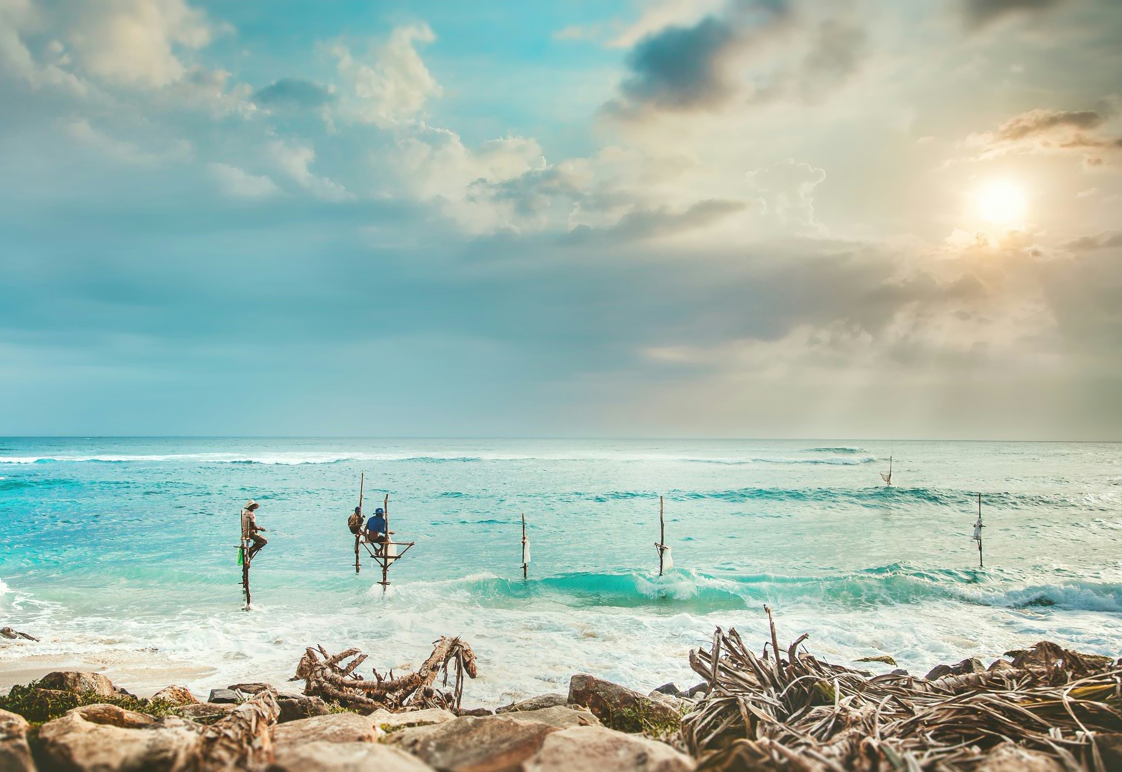Traditional stilt fishermen in the turquoise sea on Sri Lanka's deep south coast at sunset